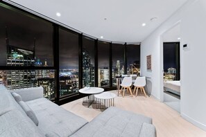 Ein modernes Zimmer mit Stadtblick, einer Couch, einem Esstisch mit Stühlen und einem Bett.