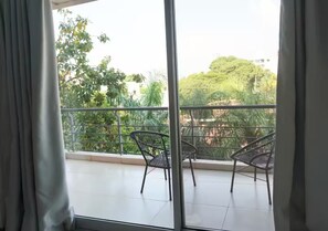 A balcony with metal railings and two chairs, overlooking a lush green area with trees and buildings. - Spacious apartment in Las Lomas | Shopping del Sol (Asunción)