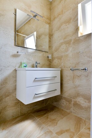 A bathroom with a white vanity, a mirror, and a towel rack. - Ohrid 1 by Interhome (Umag/Juricani)