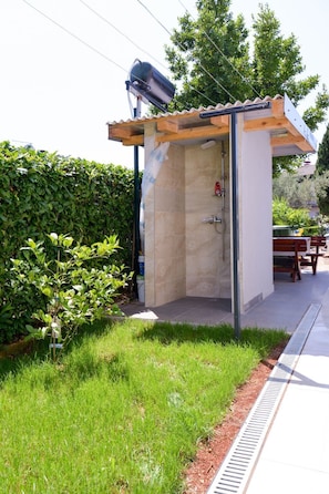 A small, enclosed outdoor shower area with a tiled wall, a wooden roof, and a metal frame. - Ohrid 1 by Interhome (Umag/Juricani)