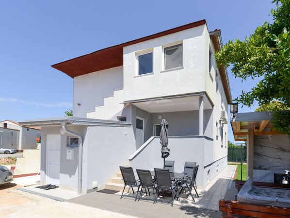 A two-story building with a balcony, outdoor seating, and a car parked nearby. - Ohrid 1 by Interhome (Umag/Juricani)