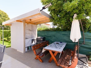 An outdoor patio with a grill, wooden table, benches, and a white umbrella. - Ohrid 1 by Interhome (Umag/Juricani)