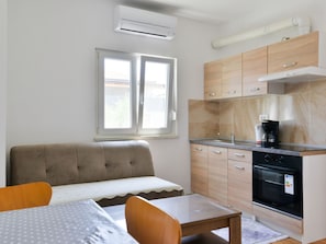 A compact kitchenette with a stove, oven, and sink. There is a sofa and a dining table with chairs. - Ohrid 1 by Interhome (Umag/Juricani)