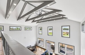 Ein modernes Interieur mit hohen Decken, mehreren Fenstern und einem Essbereich mit Aussicht.