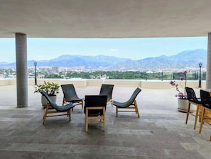 Eine Terrasse mit vier Liegestühlen, einem Tisch und Topfpflanzen.