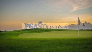 Un campo da golf con un grande cartello che riporta 'PGA Ocean's 4' e bandierine sul green.