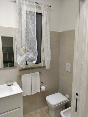 A bathroom with a toilet, sink, and a window with a curtain. - Sea less than a minute's walk away, Terme Luigiane, Wellness,Port of Cetraro (Marina)
