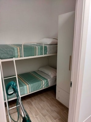 Camera con letto a castello e aspirapolvere nell'angolo.