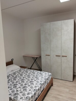 A bedroom with a bed, a wardrobe, and a small ironing board. - Sea less than a minute's walk away, Terme Luigiane, Wellness,Port of Cetraro (Marina)