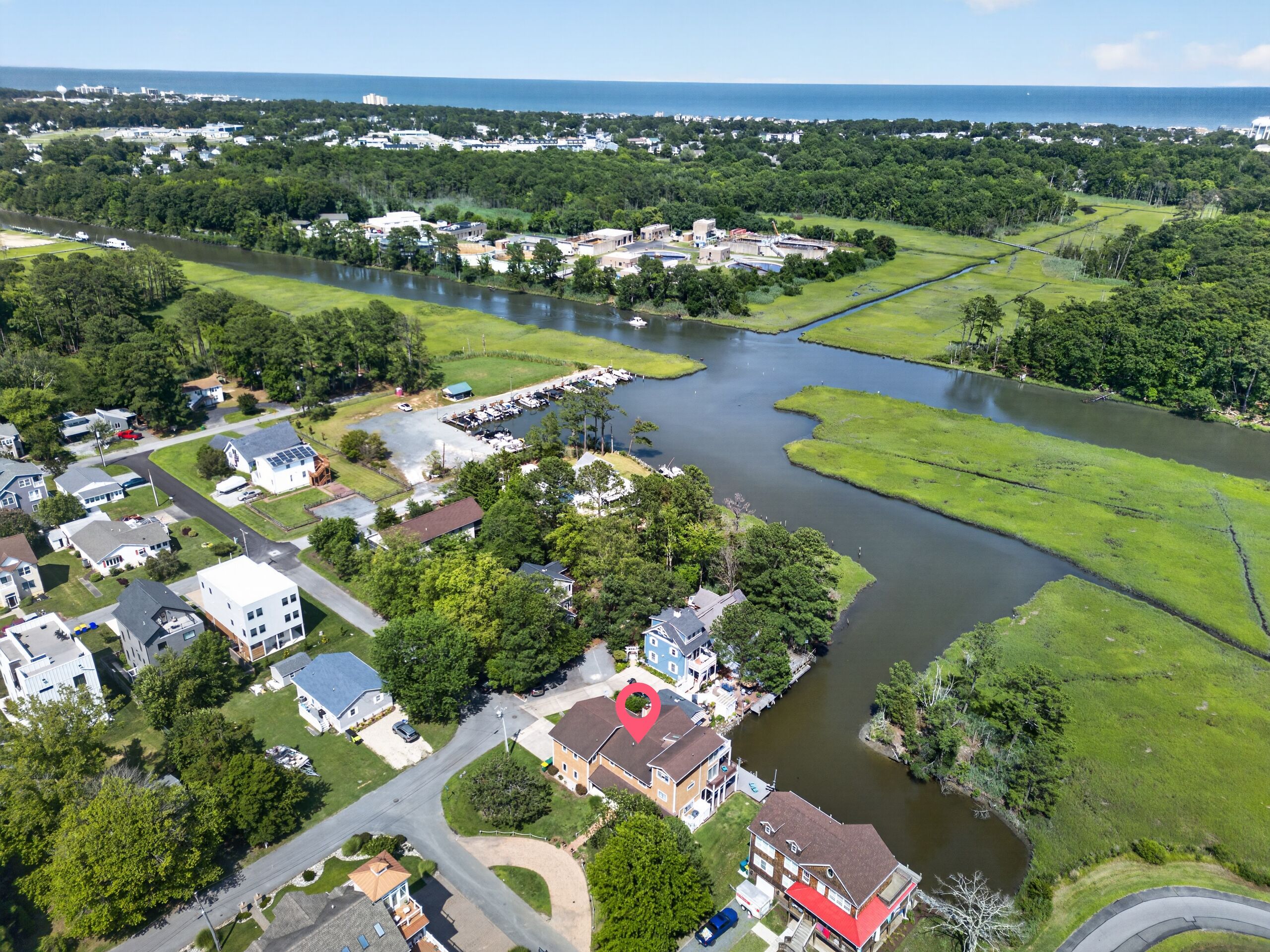 An aerial view of a residential area with houses, a river, and a marina.