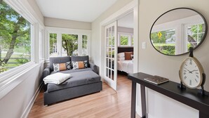Een moderne kamer met een grijze bank, een ronde spiegel en een houten vloer.