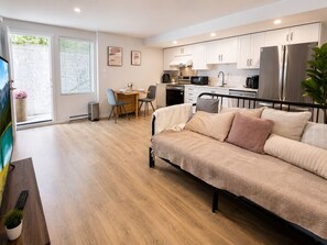 Um apartamento moderno com cozinha compacta, espaço para refeições e uma cama.