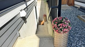A concrete staircase leading to a wooden deck, a metal railing, and a flower pot with pink flowers. - Cozy South Surrey Private One-Bedroom - 2 beds - (Surrey)