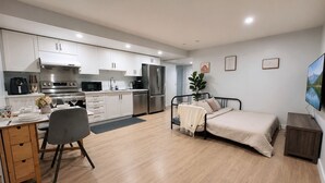 A modern kitchen with white cabinets, stainless steel appliances, and a dining area with a table and chairs. - Cozy South Surrey Private One-Bedroom - 2 beds - (Surrey)