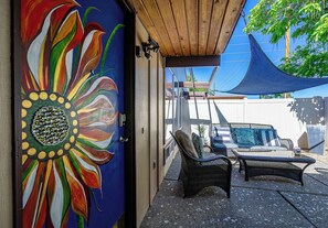 A room with a colorful flower mural, wicker furniture, and a covered outdoor area with a blue canopy.