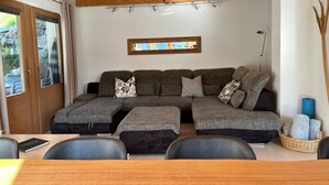 Un salon confortable avec un canapé d’angle, une table à manger et des chaises.