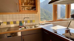 Une cuisine avec une fenêtre donnant sur les montagnes, un évier et des placards.