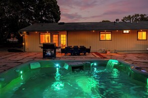Ein Haus mit Whirlpool, Sitzgelegenheit im Freien und einer Terrasse.
