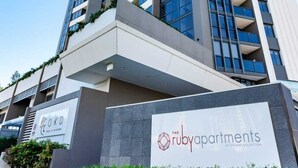 Un immeuble imposant, avec une enseigne indiquant « The Ruby Apartments » à sa base.