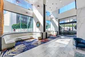 Eine moderne Lobby mit einer gebogenen Sitzecke, großen Fenstern und hängenden Pendelleuchten.