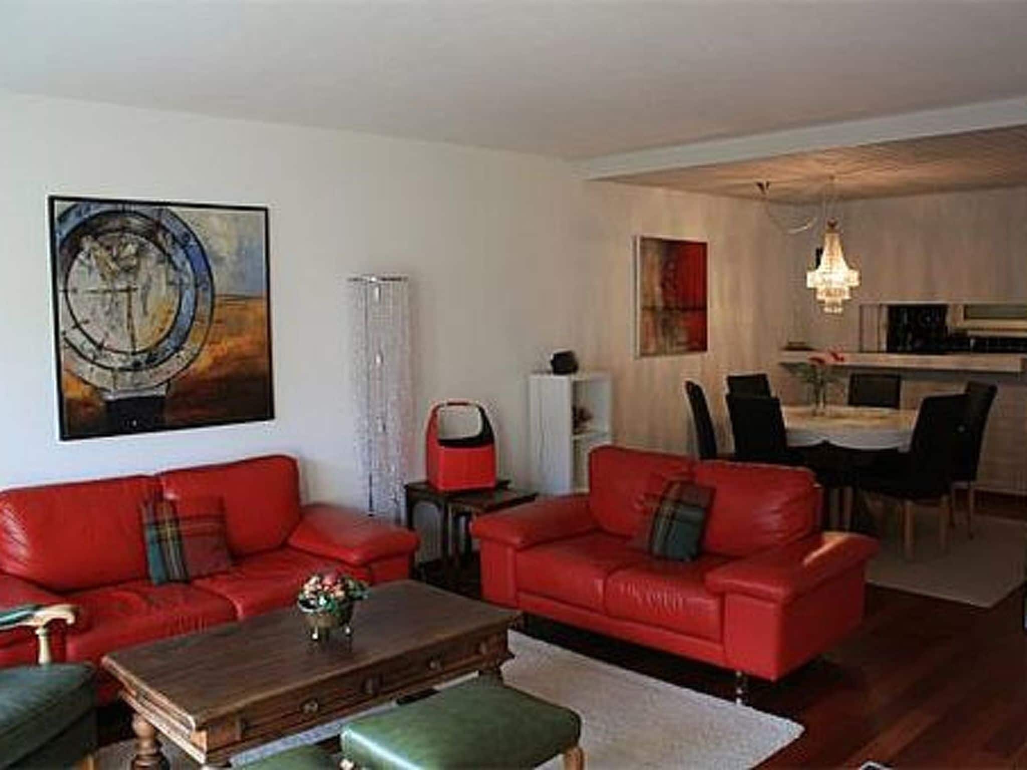 A living room with red sofas, a coffee table, and a painting on the wall.