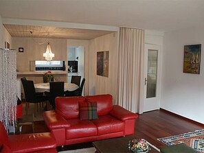 A living room with a red leather sofa, a dining area with a chandelier, and a kitchen in the background. - Brentsch Park, (Scuol) by Interhome (Scuol)
