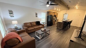 A modern living room with a sofa, coffee table, and a dining area with chairs.