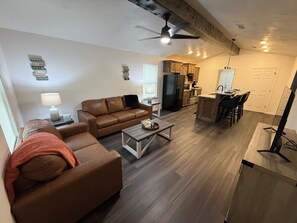 A modern living room with a sofa, coffee table, and a dining area with chairs.