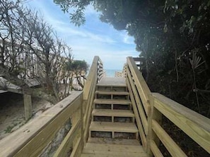 Eine Holztreppe führt zu einem Strand mit Blick aufs Meer.