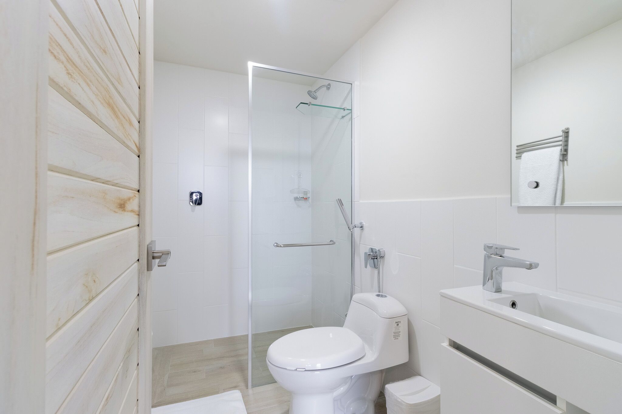 Un baño con inodoro, ducha envuelta en vidrio, lavabo y espejo.