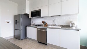 A modern kitchen with stainless steel appliances, white cabinetry, and a granite countertop. - CASA PARAISO: Spacious 3-bedroom cozy apartment just a few meters from the ocean (Chame)