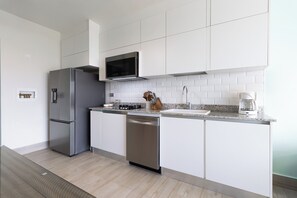 Eine moderne Küche mit Edelstahlgeräten, weißen Schränken und einer Arbeitsplatte aus Granit.