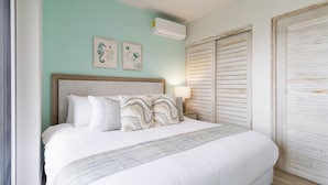 A bedroom with a bed, wall art, an air conditioner, and a wooden wardrobe. - CASA PARAISO: Spacious 3-bedroom cozy apartment just a few meters from the ocean (Chame)