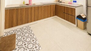 A modern kitchen with white cabinets, a wooden countertop, and a patterned rug.
