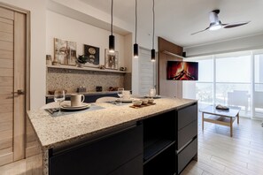 Eine moderne Küche mit Granit Arbeitsplatten, einem Essbereich mit Tisch und Stühlen, einem an der Wand befestigten Fernseher und einem Deckenventilator.