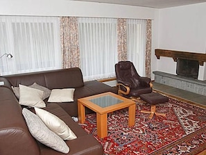 A living room with a brown sofa, a wooden coffee table, a patterned rug, and a fireplace. - Brentsch Park, (Scuol) by Interhome (Scuol)