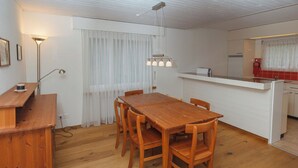Una cocina compacta con una mesa y sillas de madera, una pequeña isla con un lavamanos y un refrigerador.