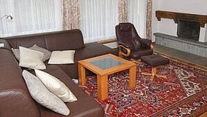 Una sala de estar con un sofá marrón, una mesa de centro de madera, un tapiz estampado y una chimenea.