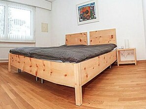 A wooden bed in a room with a window and a picture on the wall. - Brentsch Park, (Scuol) by Interhome (Scuol)