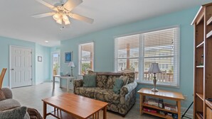 A living room with a sofa, a coffee table, a ceiling fan, and a bookshelf. - 4 Bedroom, 4 Bathroom, Dunes Home, PET FRIENDLY (Supply)