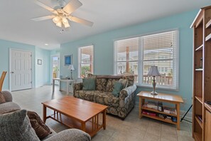 A living room with a sofa, a coffee table, a ceiling fan, and a bookshelf. - 4 Bedroom, 4 Bathroom, Dunes Home, PET FRIENDLY (Supply)