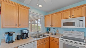 A kitchen with wooden cabinets, a microwave, an oven, a coffee maker, and a dishwasher. - 4 Bedroom, 4 Bathroom, Dunes Home, PET FRIENDLY (Supply)