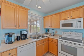 A kitchen with wooden cabinets, a microwave, an oven, a coffee maker, and a dishwasher. - 4 Bedroom, 4 Bathroom, Dunes Home, PET FRIENDLY (Supply)