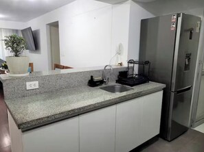 A kitchen with a granite countertop, stainless steel refrigerator, and a built-in oven. - Aura Bella - Prime Location! Walking Distance to Malls, Restaurants & Services. (Lima)