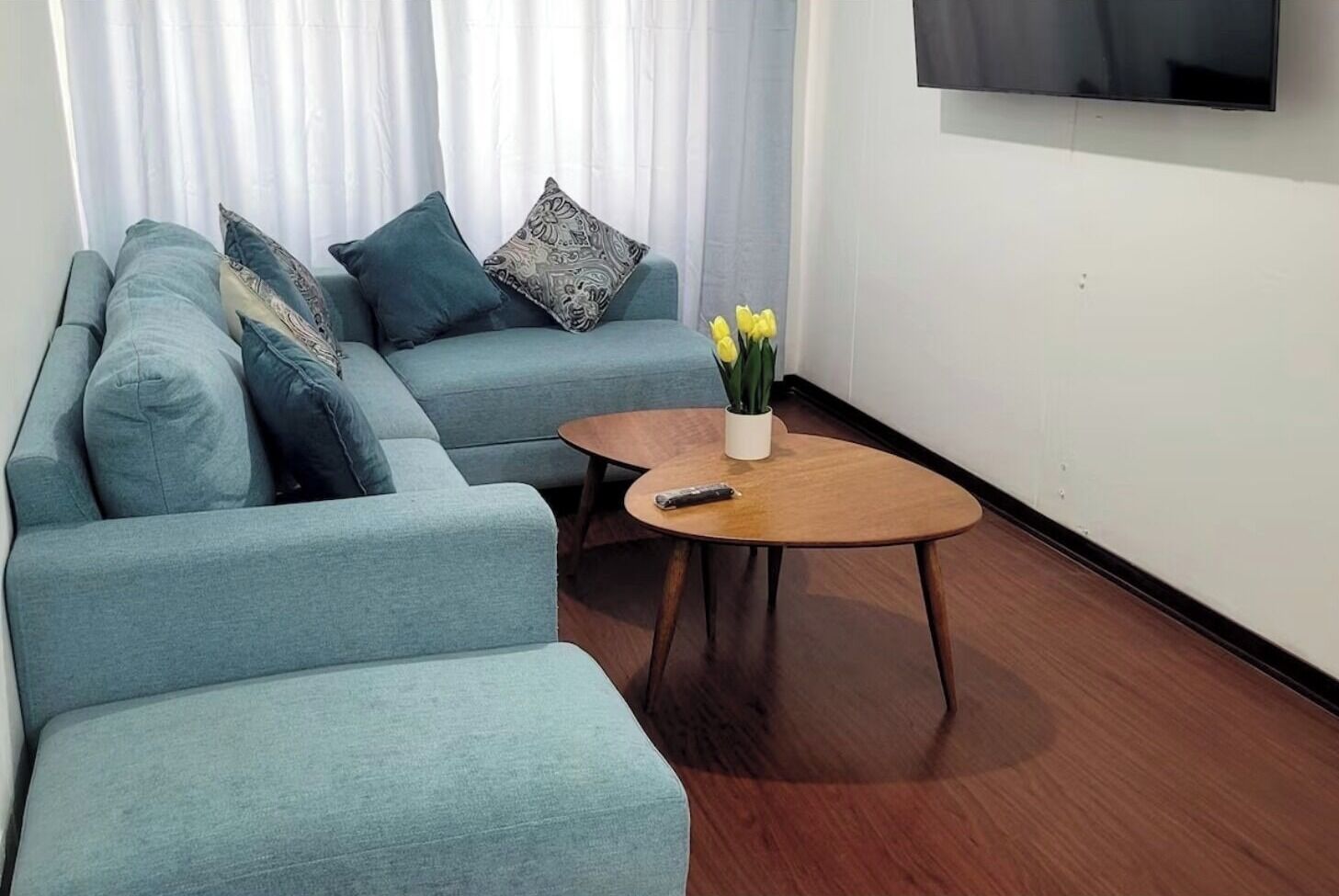 Un salon avec un canapé, une table basse et un téléviseur fixé au mur.