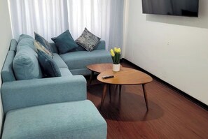 A living room with a sofa, a coffee table, and a TV mounted on the wall. - Aura Bella - Prime Location! Walking Distance to Malls, Restaurants & Services. (Lima)