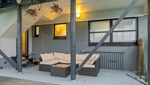 A covered outdoor seating area with a sofa, a hanging plant, and a staircase. - Spacious 5-Bedroom Family Home Near Lake Rotorua & Rotorua CBD (Rotorua)