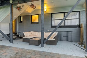 A covered outdoor seating area with a sofa, a hanging plant, and a staircase. - Spacious 5-Bedroom Family Home Near Lake Rotorua & Rotorua CBD (Rotorua)