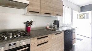 Una cocina moderna con electrodomésticos de acero inoxidable, armarios de madera y lavavajillas negro.