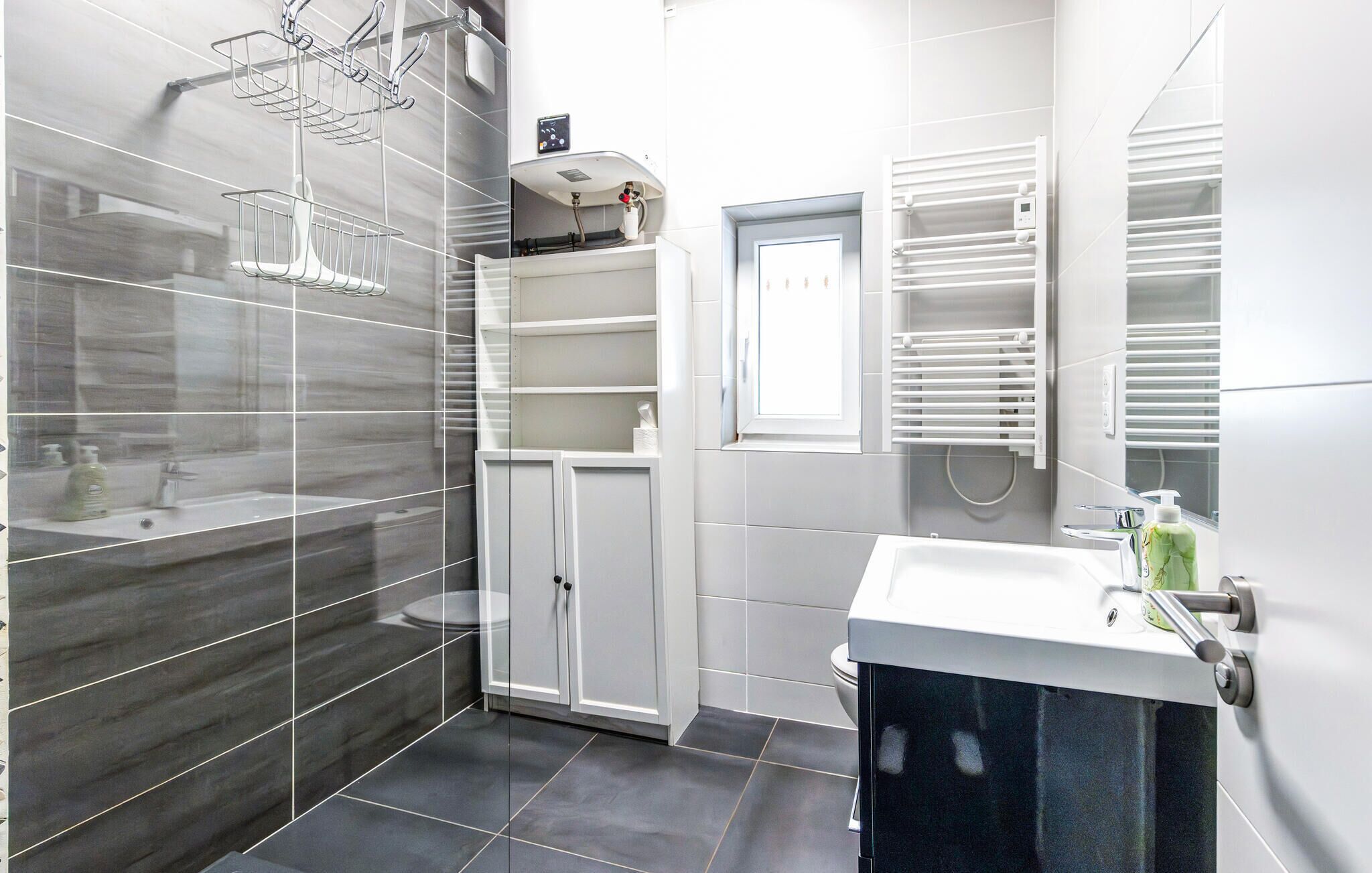 A modern bathroom with a glass shower enclosure, a white vanity with a sink, and a built-in medicine cabinet.